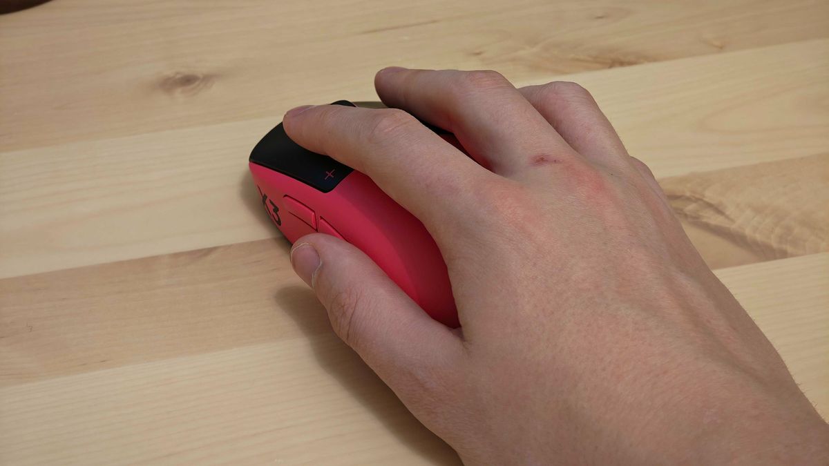 The Logitech G pro X3 Superstrike gaming mouse in pink placed on a light-coloured wooden desk.