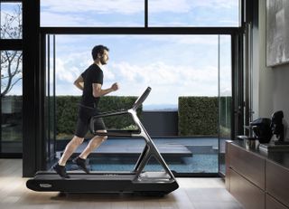 A man running on a treadmill next to an open sliding door.