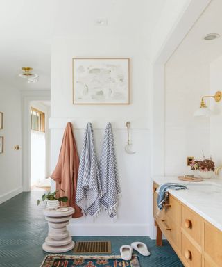 Hooks with towels next to wooden vanity with marble top
