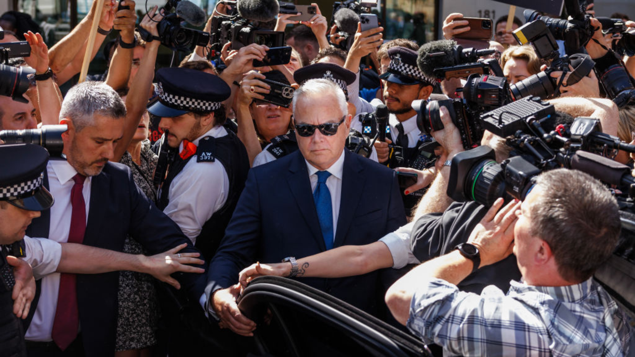 Huw Edwards opens a car door surrounded by police and crowds of photographers and members of the public outside Westminster Magistrates&#039; Court