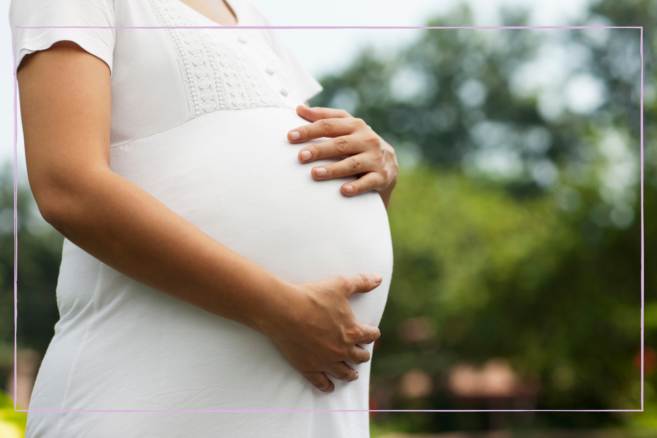 pregnant woman in white dress holding stomach