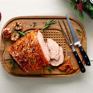 wooden carving board with knife fork and meat