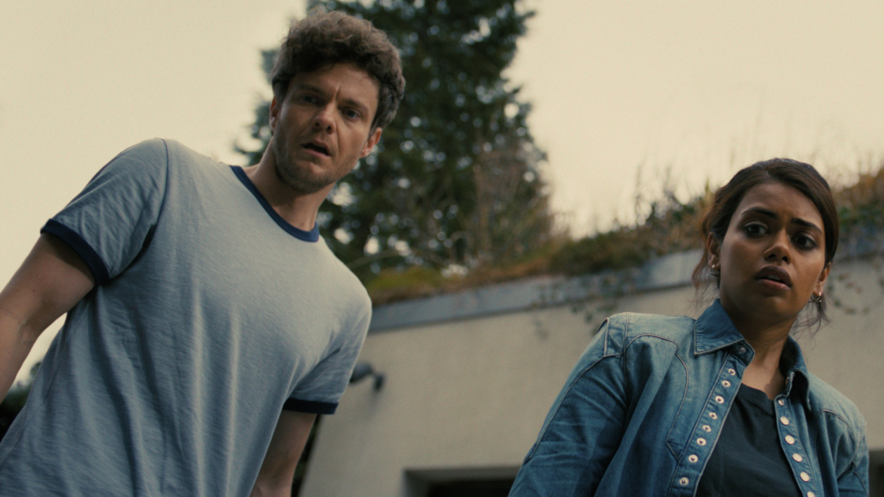 A scared Jack Quaid and Megan Suri look at something disturbing off camera in Companion.