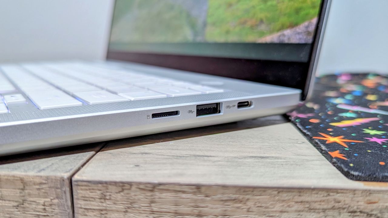 Asus Zephyrus G14 (2024) open on a brown table, highlighting the ports on the right side, including a Type-C, a Type-A, and microSD.