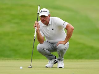 Lucas Glover reading a putt while holding his broomstick putter