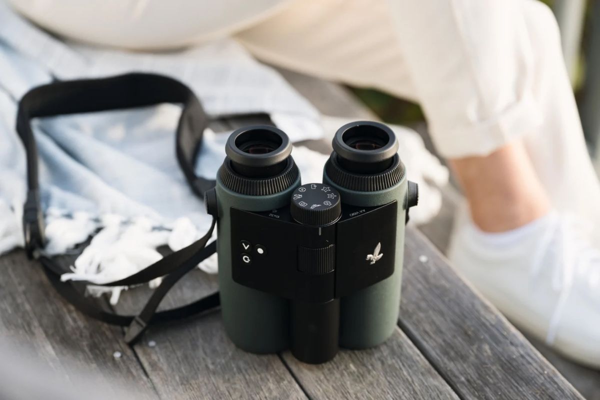 A pair of Swarovski binoculars on an orange background
