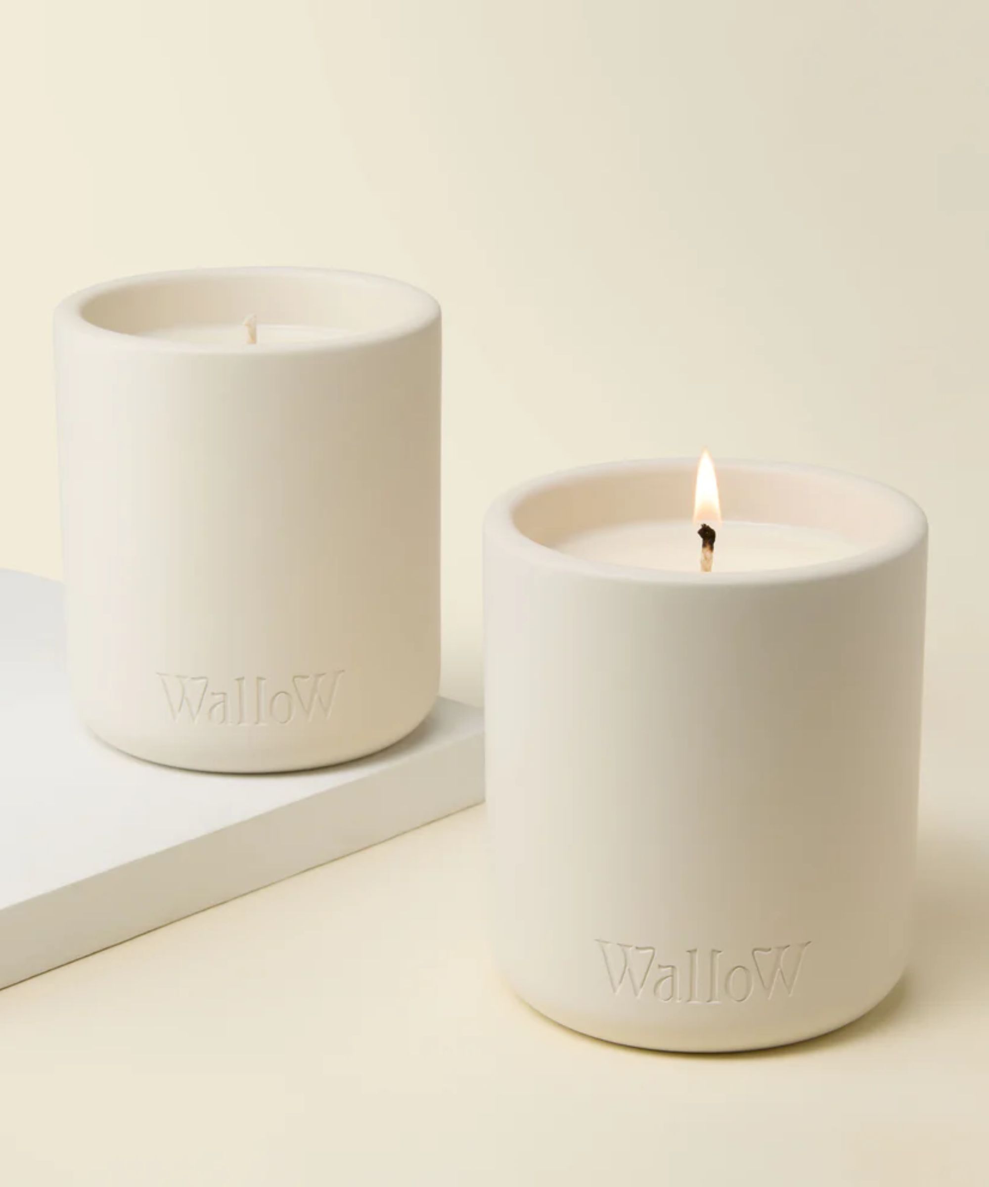 Two white candles against a cream background