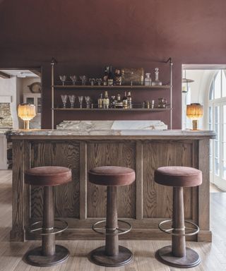 bar area with wooden bar, pink bar stools and pink walls