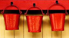 Three red buckets hang on pegs.