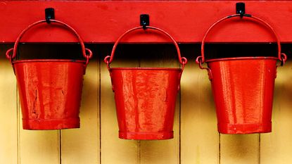 Three red buckets hang on pegs.