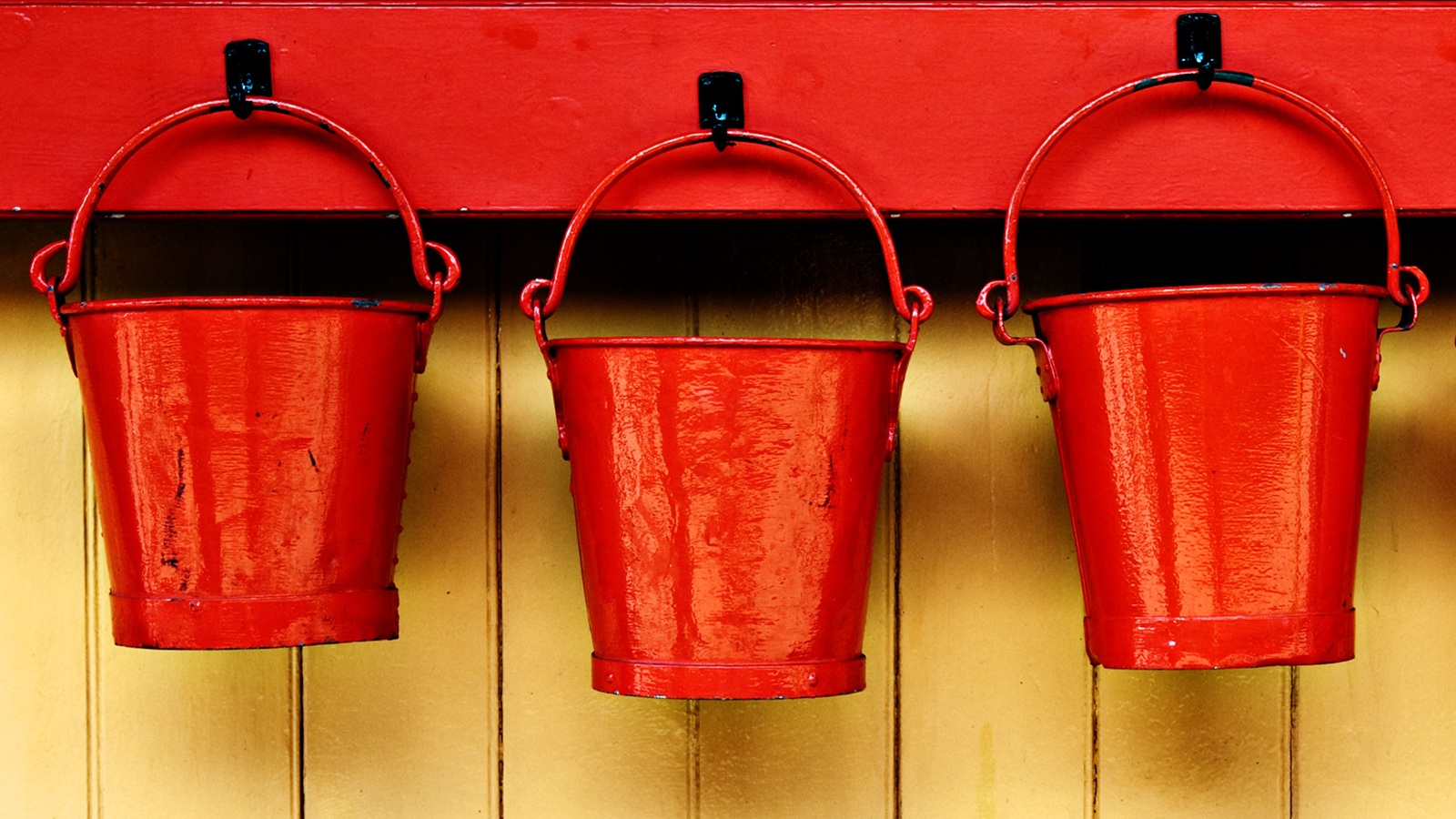 Three red buckets hang on pegs.