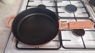 The Our Place Cast Iron Always Pan in pink on a gas stovetop