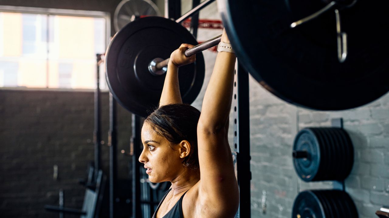 A woman performing a barbell overhead press