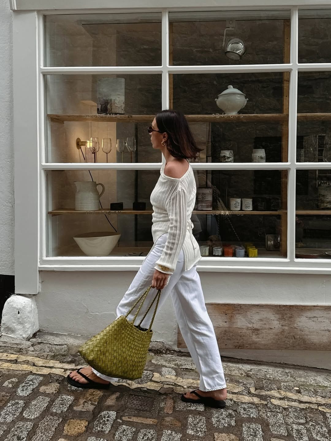 Influencer Jessica wears a white knit top with white pants and a woven leather bag.