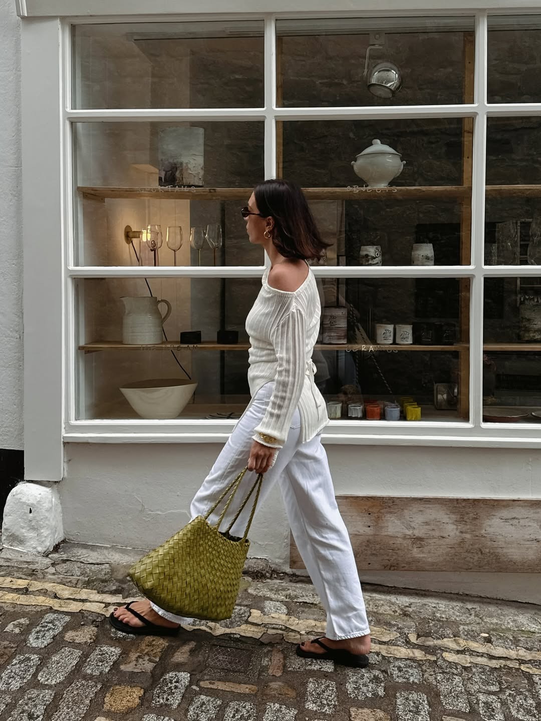 Influencer Jessica wears a white knit top with white pants and a woven leather bag.