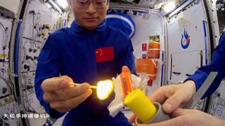 Astronauts Gui Haichao and Zhu Yangzhu light a candle aboard the Tiangong Space Station during a live lecture on Sept. 21, 2023.