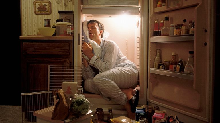 man asleep in a fridge with door open