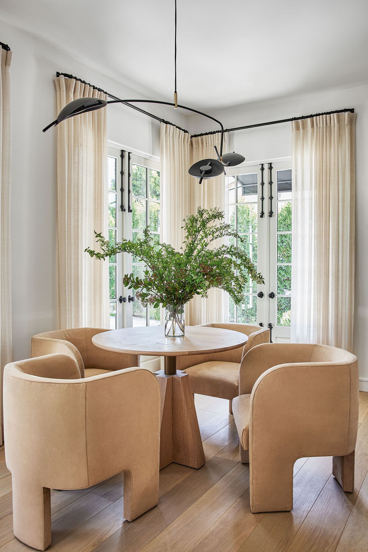 A dining area with a black artistic feature light and four neutral chairs