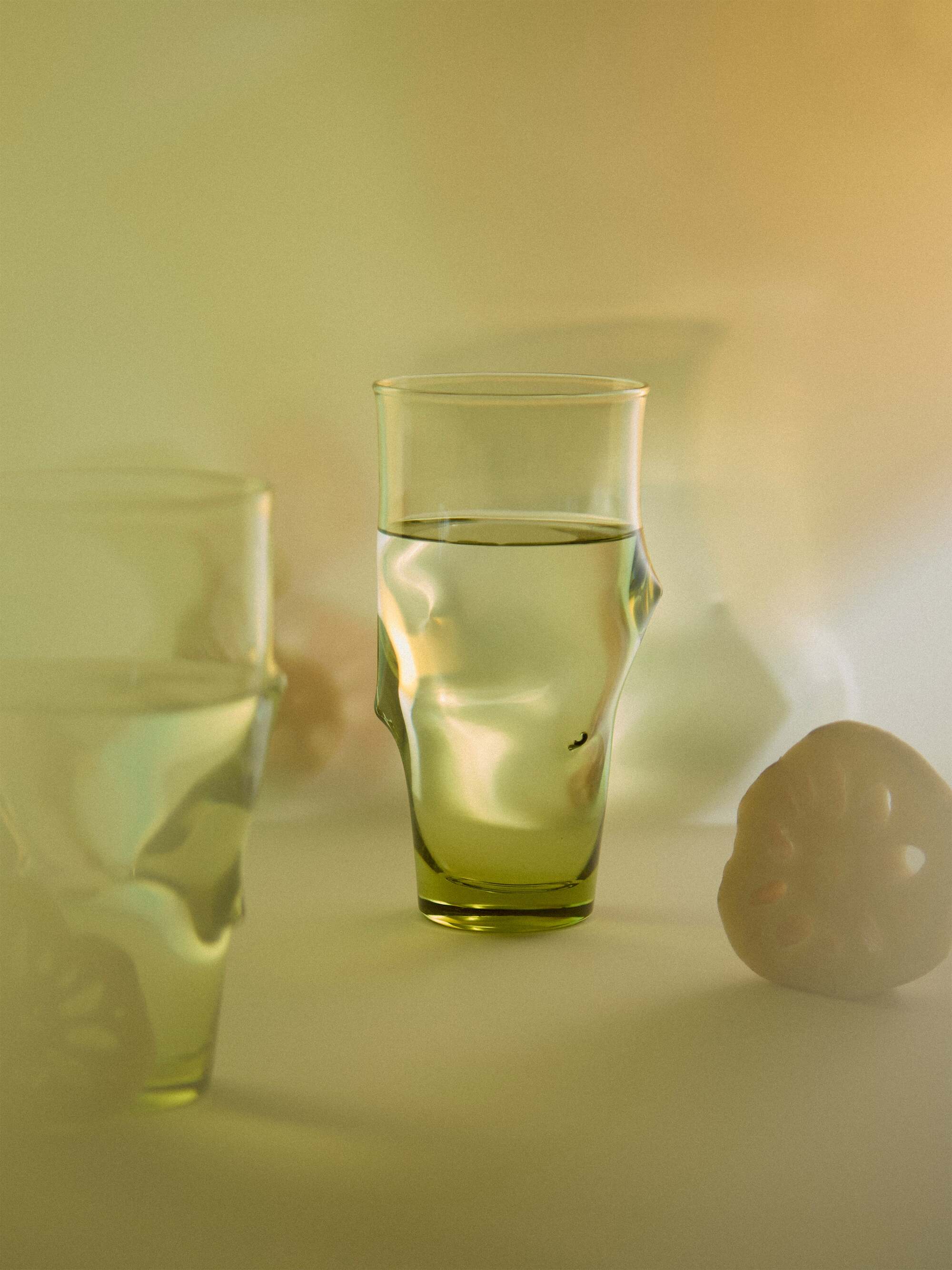 Image of an abstract green glass highball glass with a hazy/faded green background.