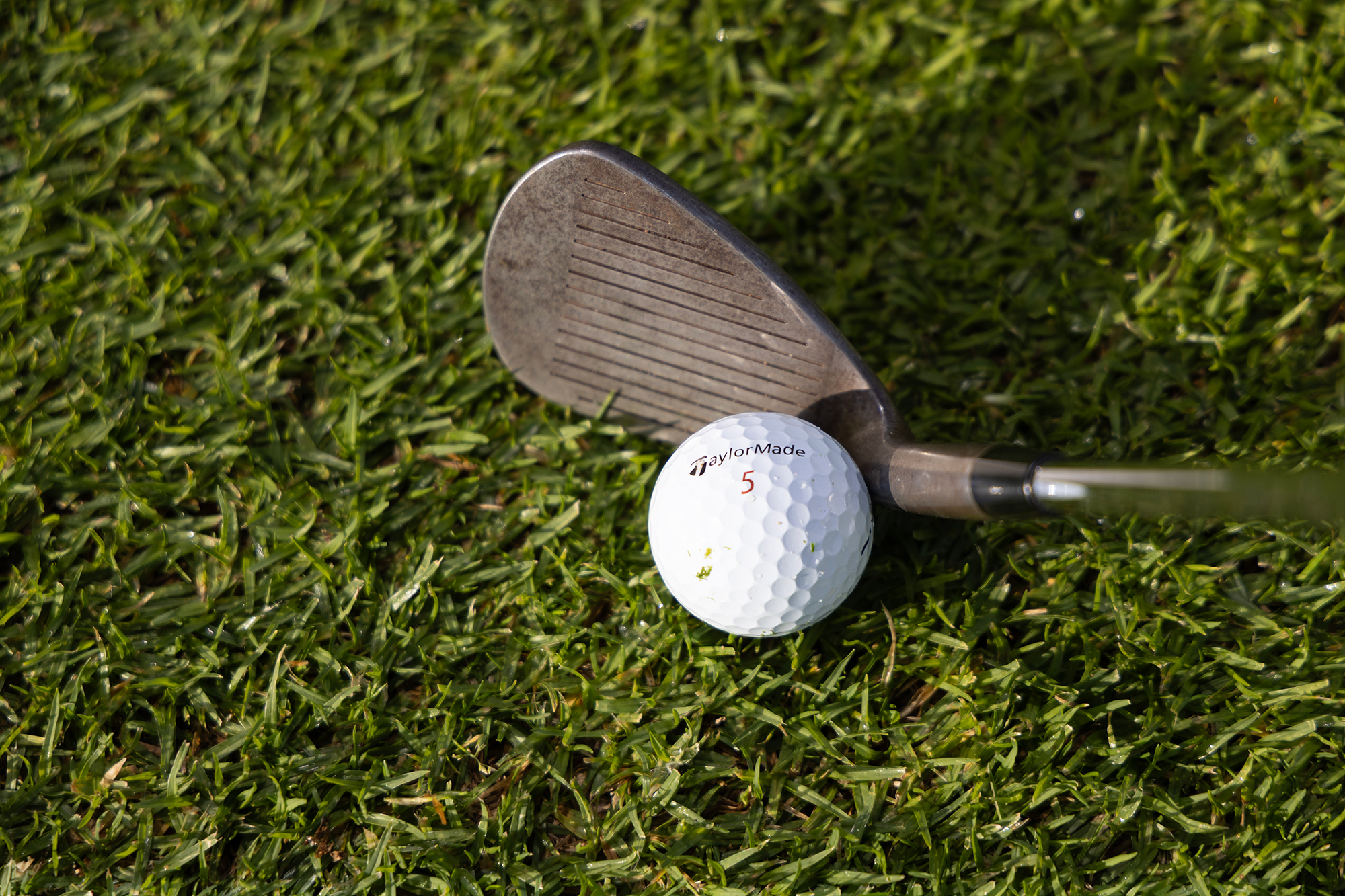 A close up image of a shank in golf, where the golf ball is making contact with the hosel of the golf club, resulting in unpredictable ball striking