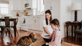 Woman and child giving cat a treat