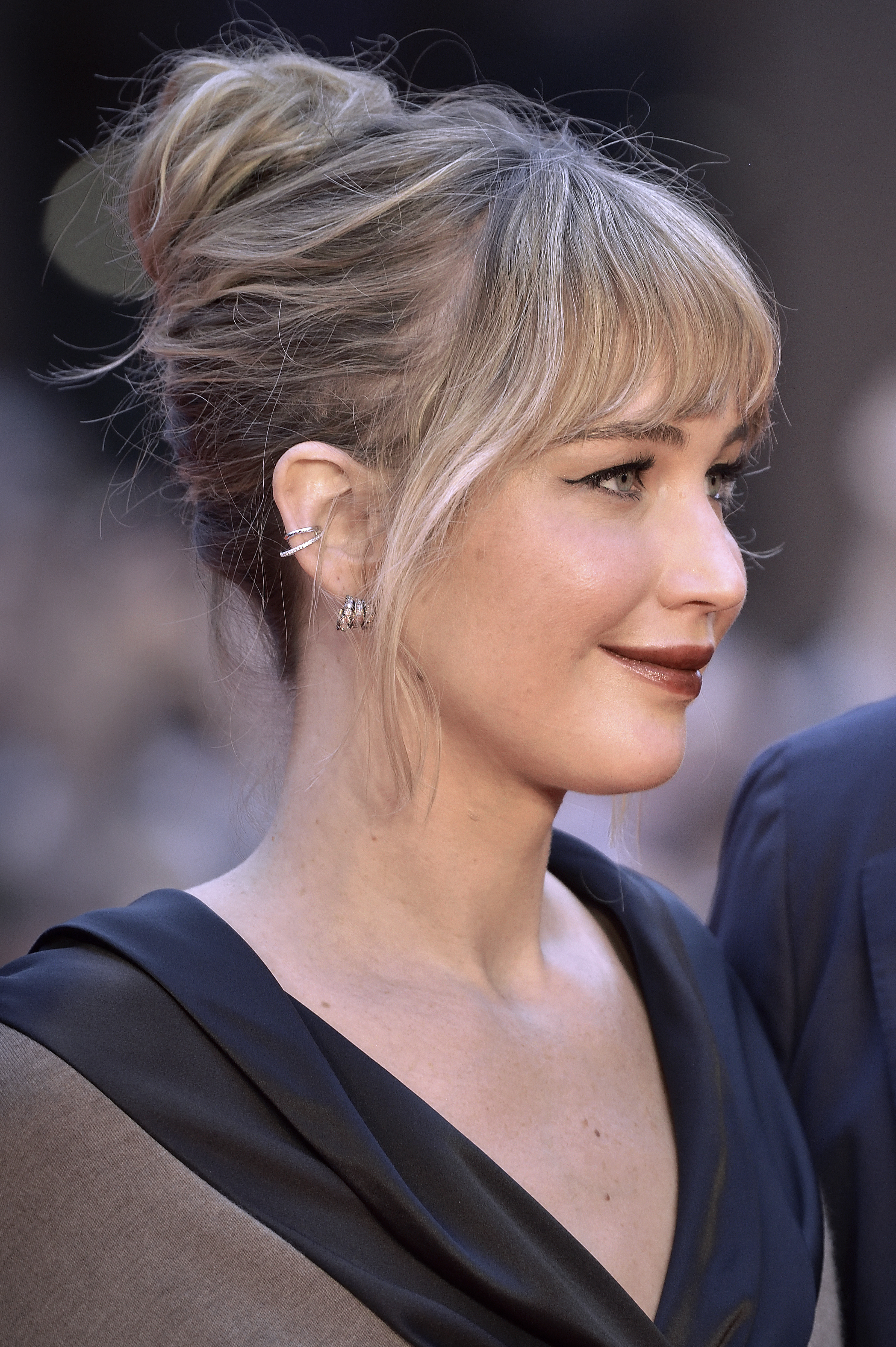 a white woman with dark blonde hair posing on a red carpet with her hair pulled into a bun