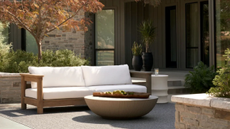 a white sofa with a wood frame on a patio with a round coffee table and lots of greenery