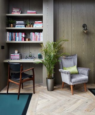 grey armchair in wooden floored froom with shelving and desk