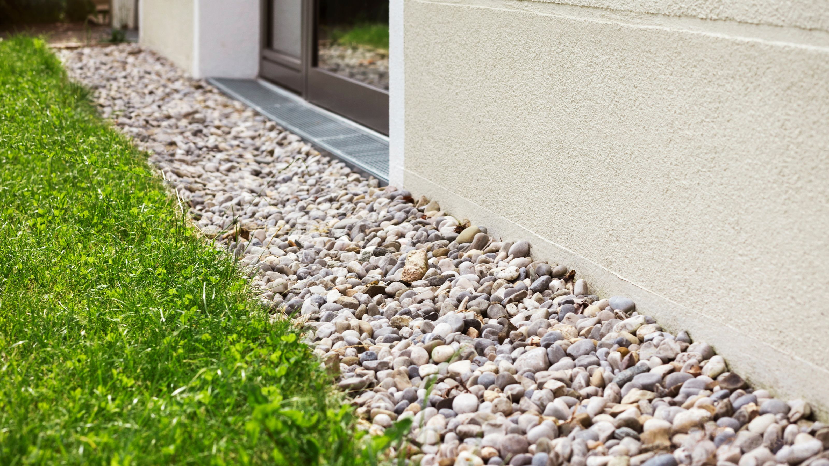 French drain with gravel running between lawn and house