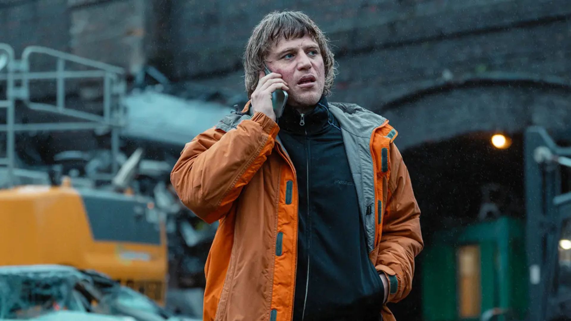Frankie talks on the phone while standing in a warehouse courtyard