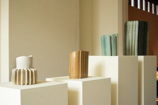 View of Floris Wubben's exhibition at SCP Pimlico Road featuring green, brown and off-white coloured ceramics on white plinths in a room with light coloured walls