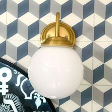 Wall light with round white shade on blue graphic tiled wall
