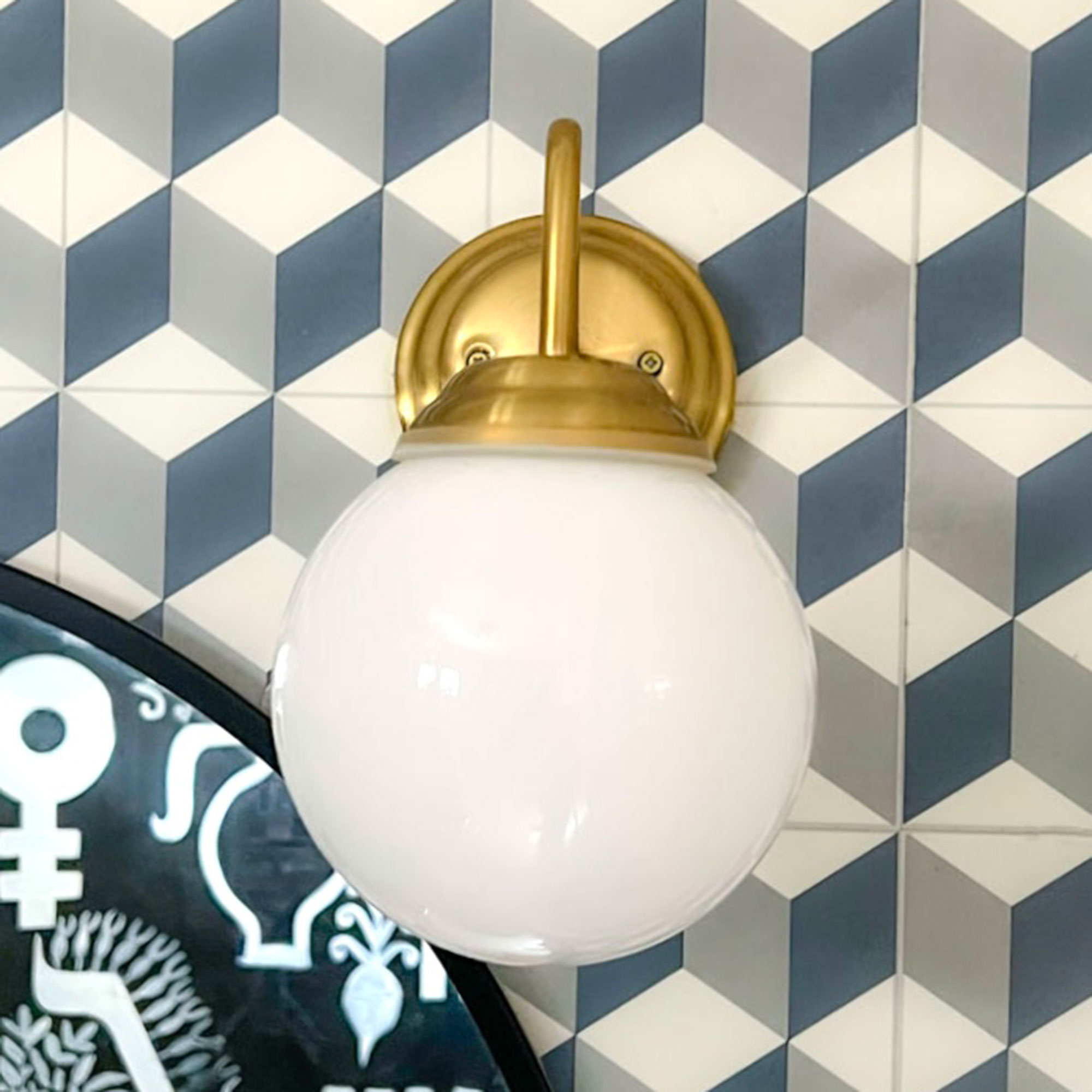Wall light with round white shade on blue graphic tiled wall