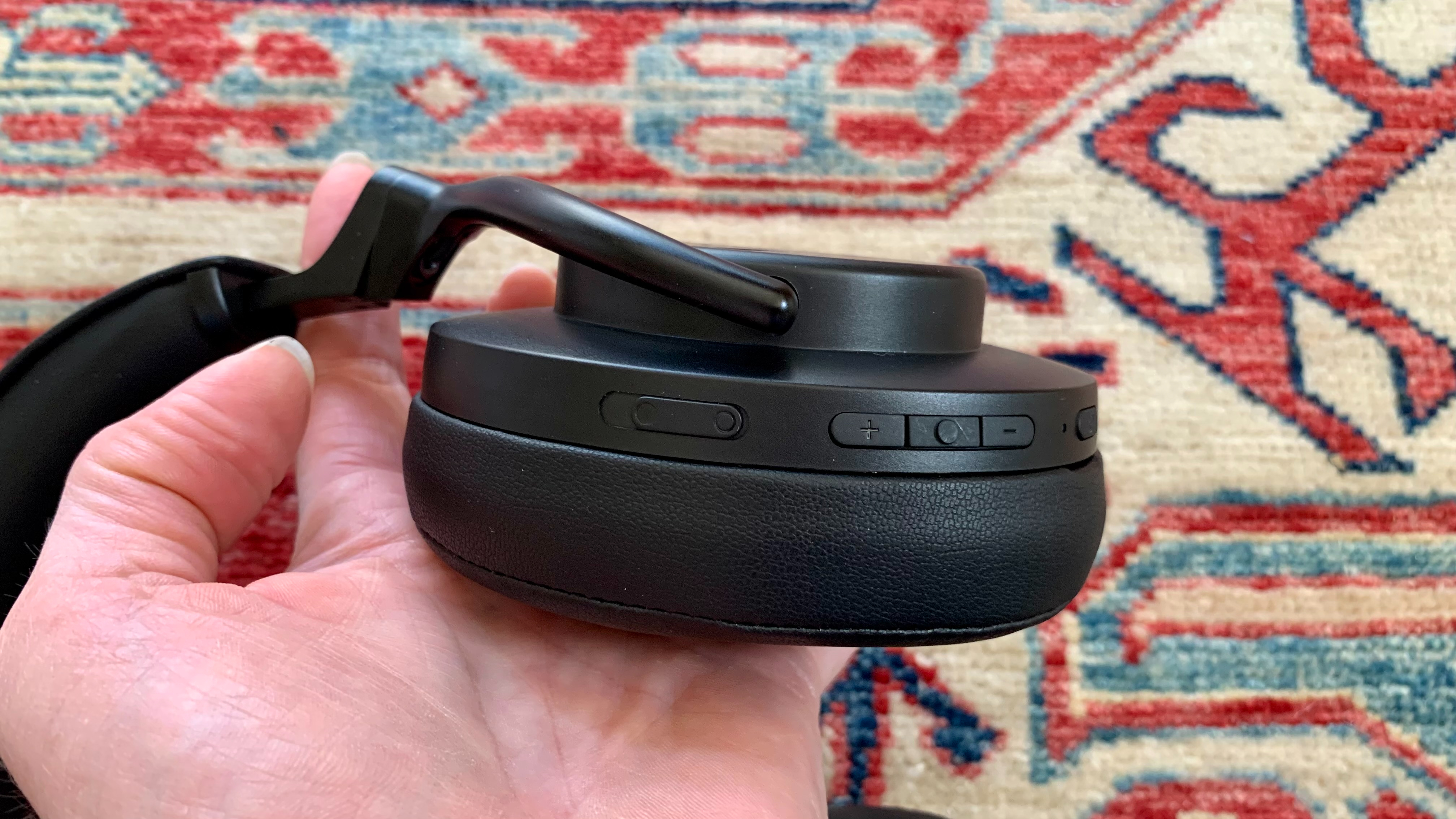 Shure Aonic 50 headphones held in a hand showing detail on the earcup