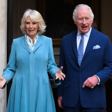 Queen Camilla wears a turquoise dress and King Charles wears a blue suit