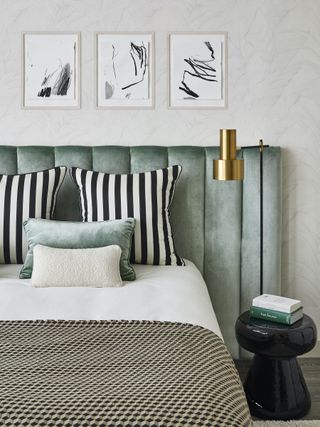 bed with pale green velvet headboard and black and white cushions