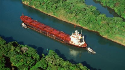 Tugs guiding cargo ship through Panama Canal