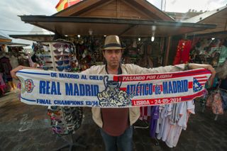 A vendor holds up a half-and-half scarf ahead of the 2014 Champions League final between Real Madrid and Atletico Madrid in Lisbon.