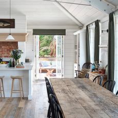 a country-style open-plan kitchen diner with open patio doors that lead into a garden