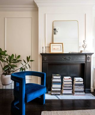 A black fireplace mantel and a dark blue velvet armchair in a studio apartment