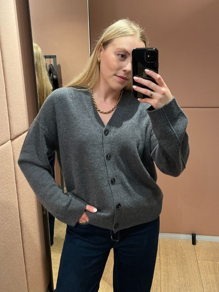 Woman wears grey v-neck cashmere cardigan and blue jeans