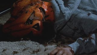 A dead child lies wearing a mask with bugs surrounding the corpse in Halloween III: Season of the Witch.