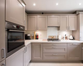 A general interior view of a small truffle taupe coloured shaker style fitted kitchen and kitchen cabinets