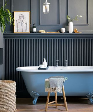 Blue painted bathroom with painted bathtub and painted blue wooden panelling