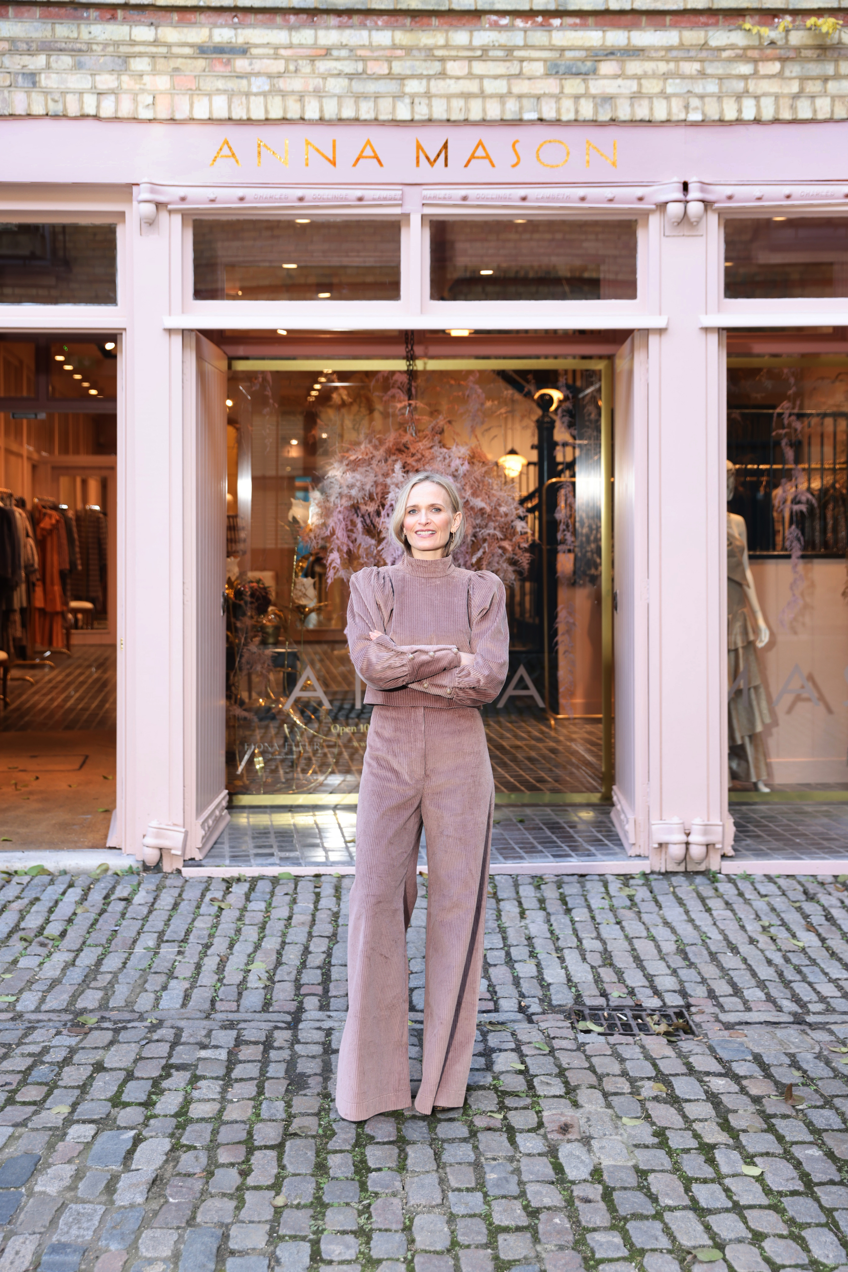 Anna Mason posing outside her shop in a pink top and pants