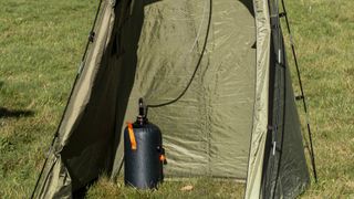 Green shower tent pitched on a meadow