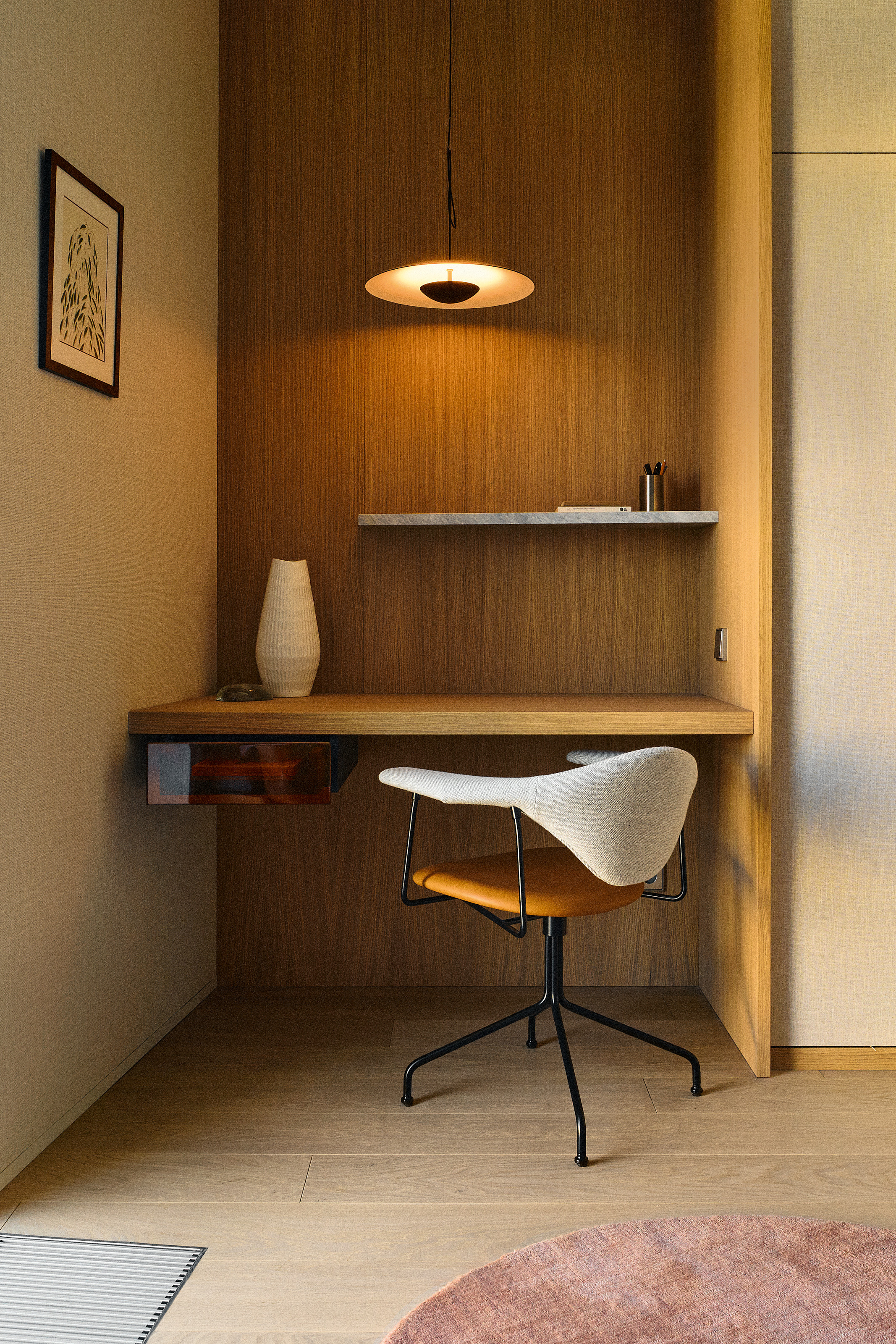 Desk area with panelled wall, built-in marble shelf, tan and cream boucle desk chair and minimalist pendant