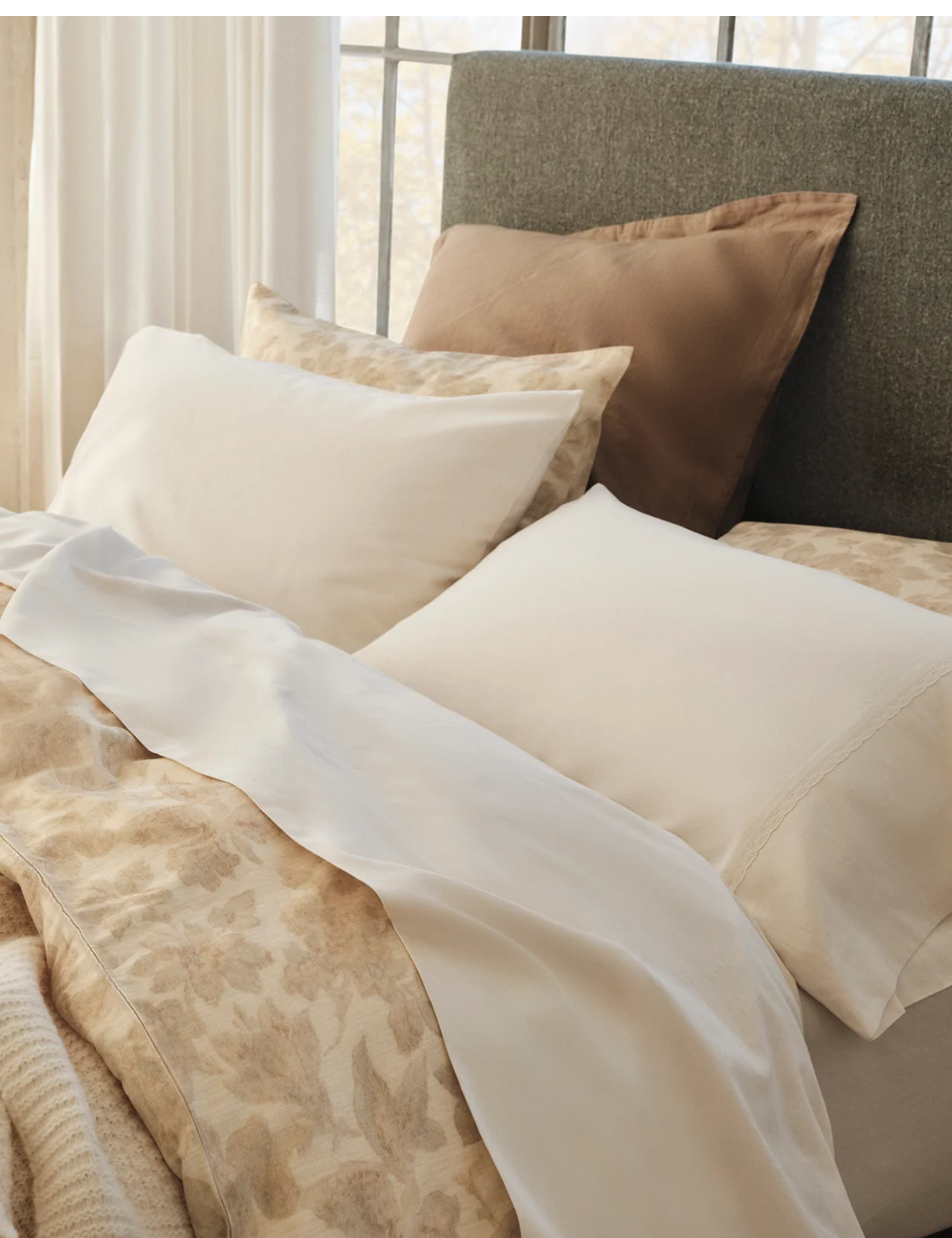 Neutral Coyuchi bed sheets photographed in a sunlit living room