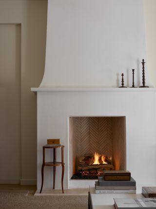 A white minimalist fireplace with three wooden candle sticks as decor
