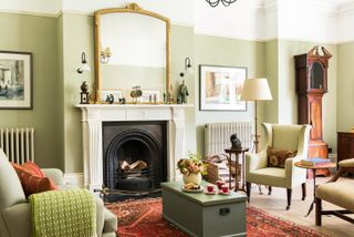 green living room with fireplace, armchairs and mirror